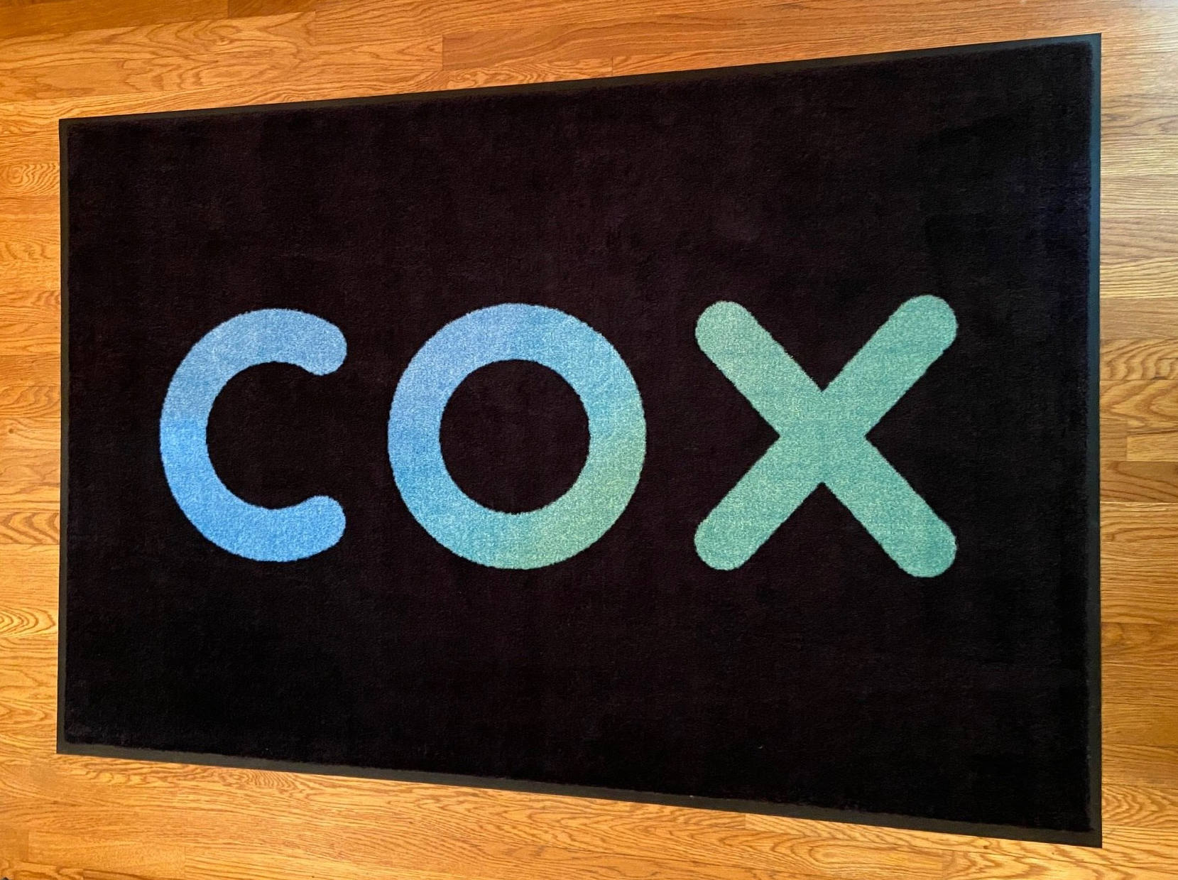 Black sign with colorful “COX” letters on a wooden wall