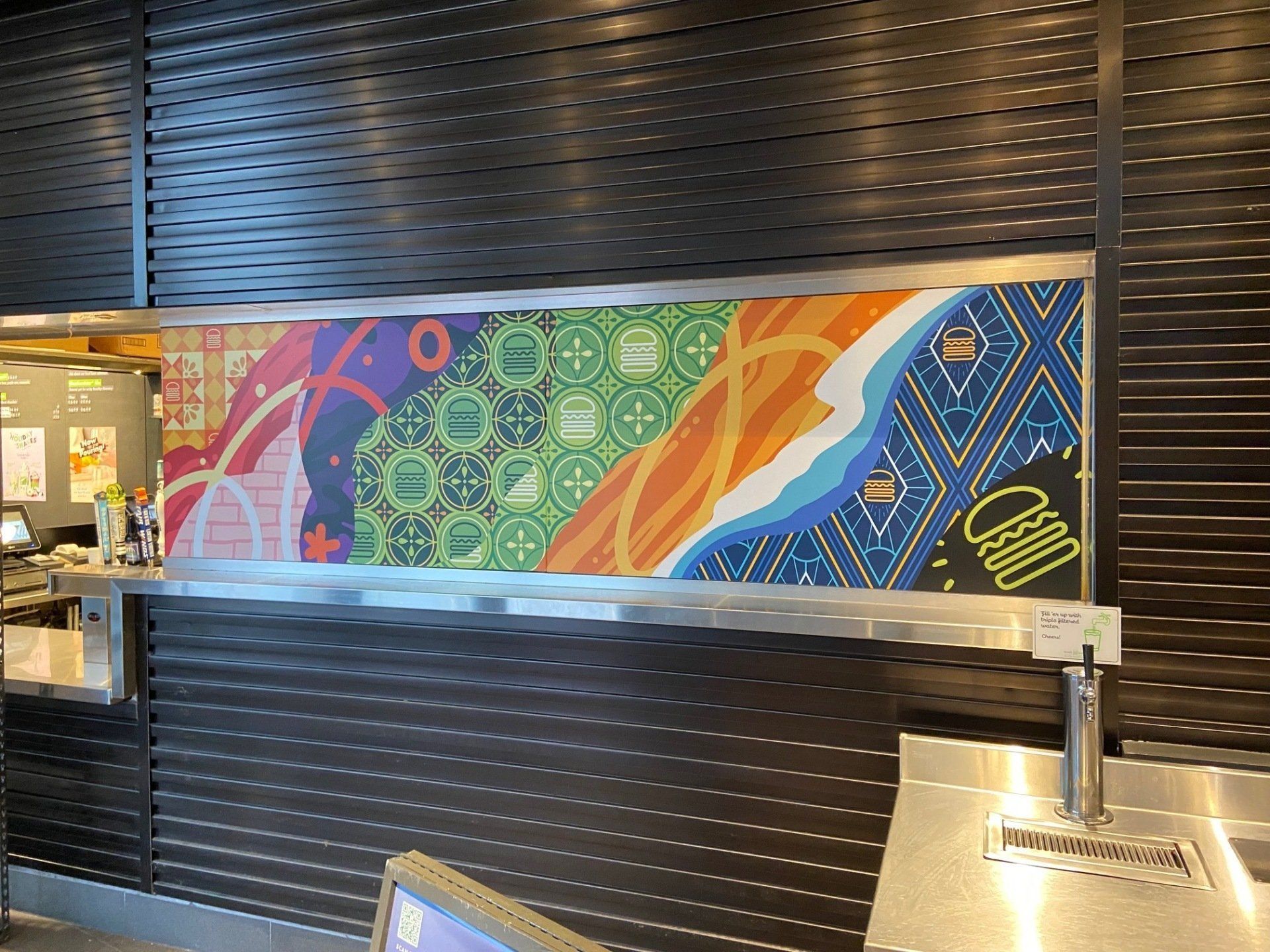 Colorful mural on a dark metal wall behind a counter in a modern interior