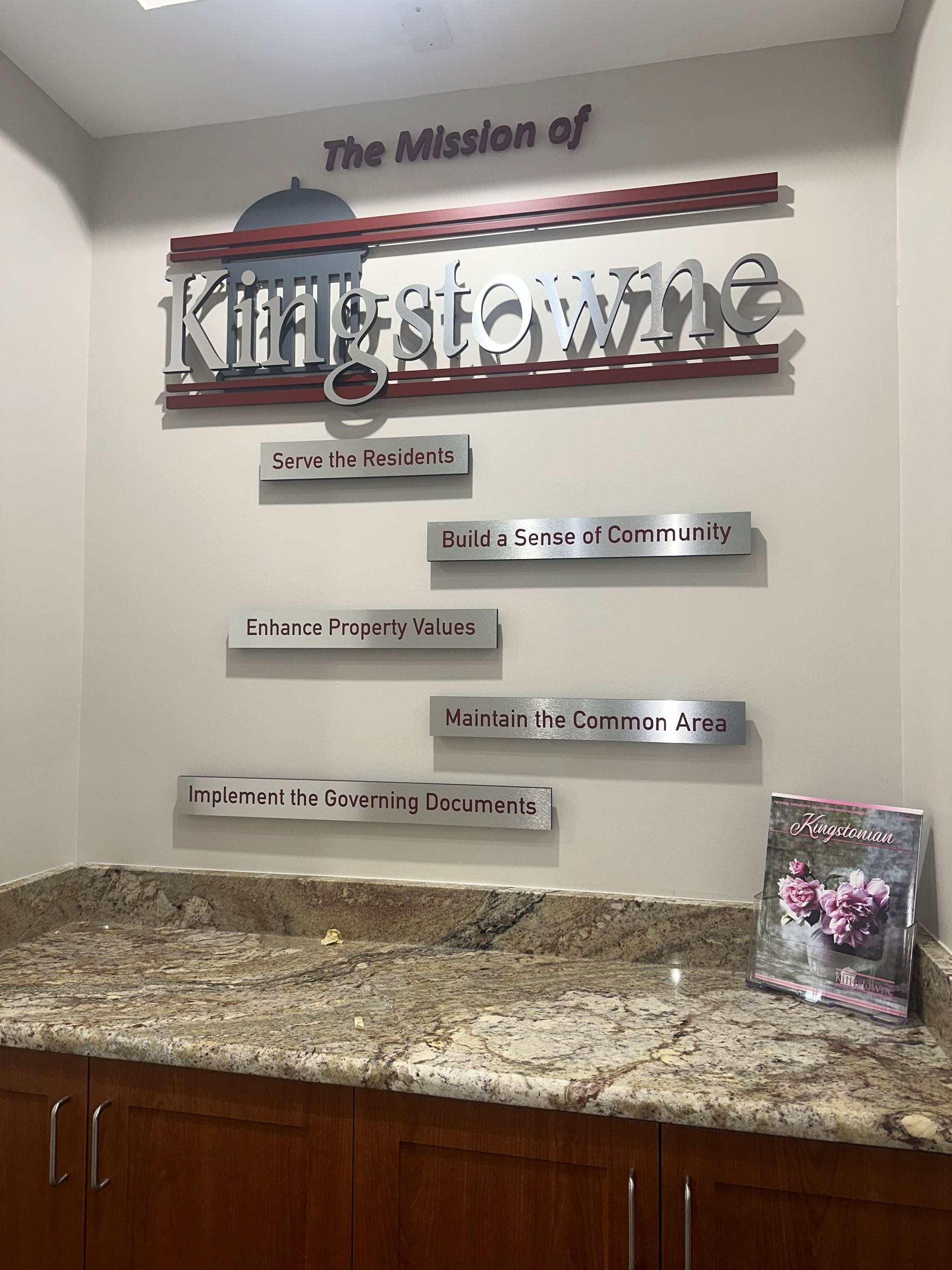 Wall display with “The Mission of Kingsville” lettering above a granite countertop and wooden cabinets
