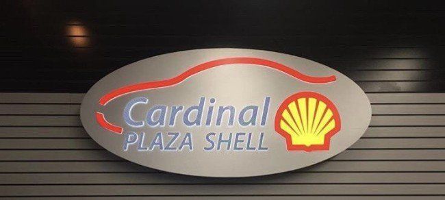 Cardinal Plaza Shell sign with red and yellow logo on a black wall