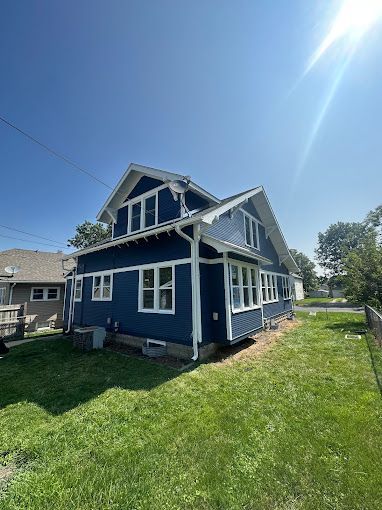 A blue house with white trim is sitting on top of a lush green lawn.