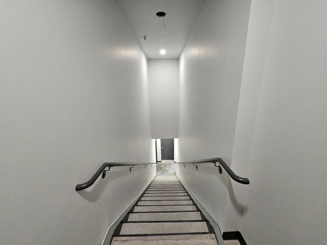 A long hallway with stairs leading up to a door.