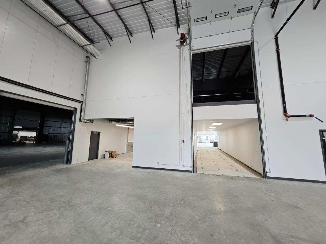 A large warehouse with a lot of white walls and a concrete floor.