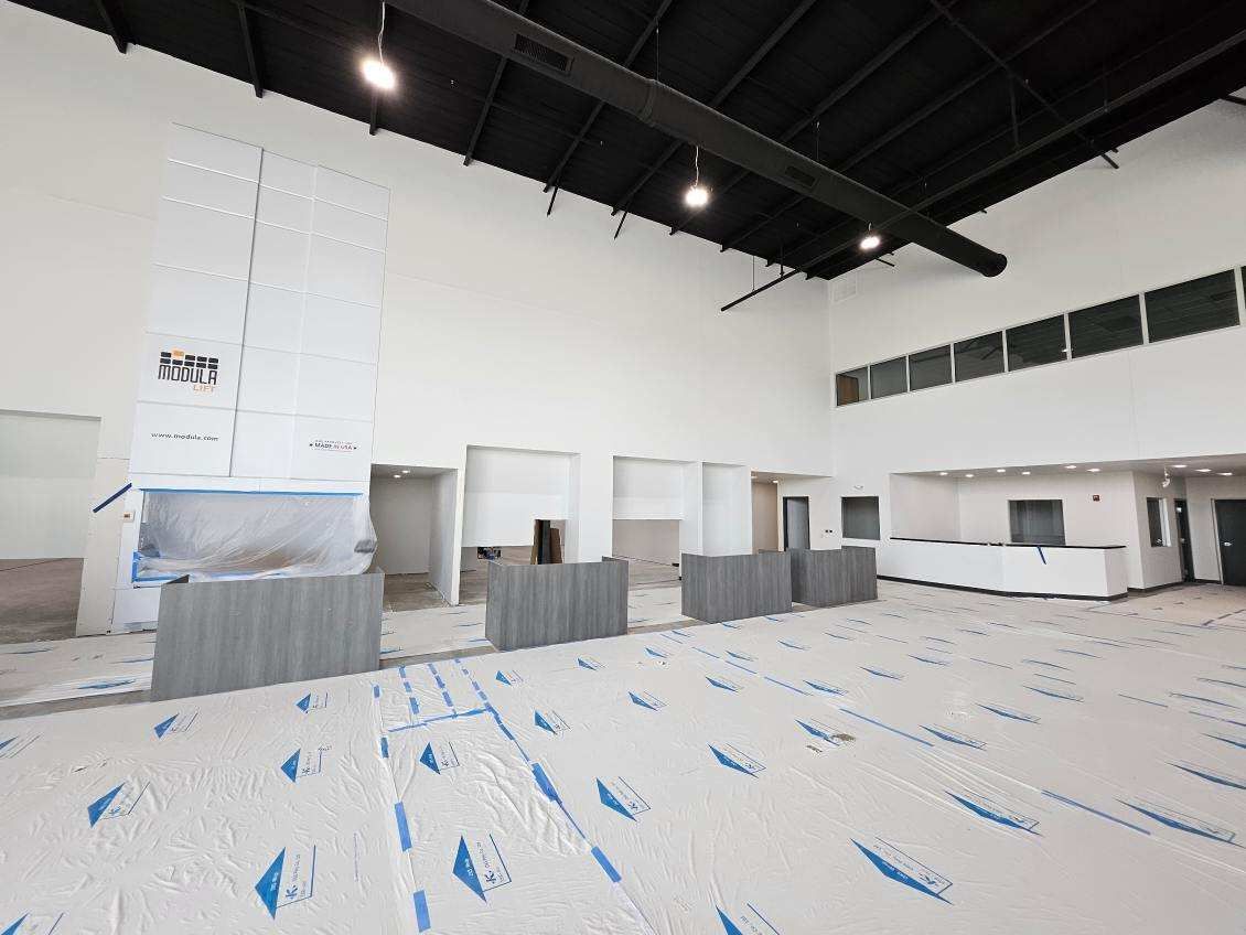 A large empty room with white walls and blue tape on the floor.