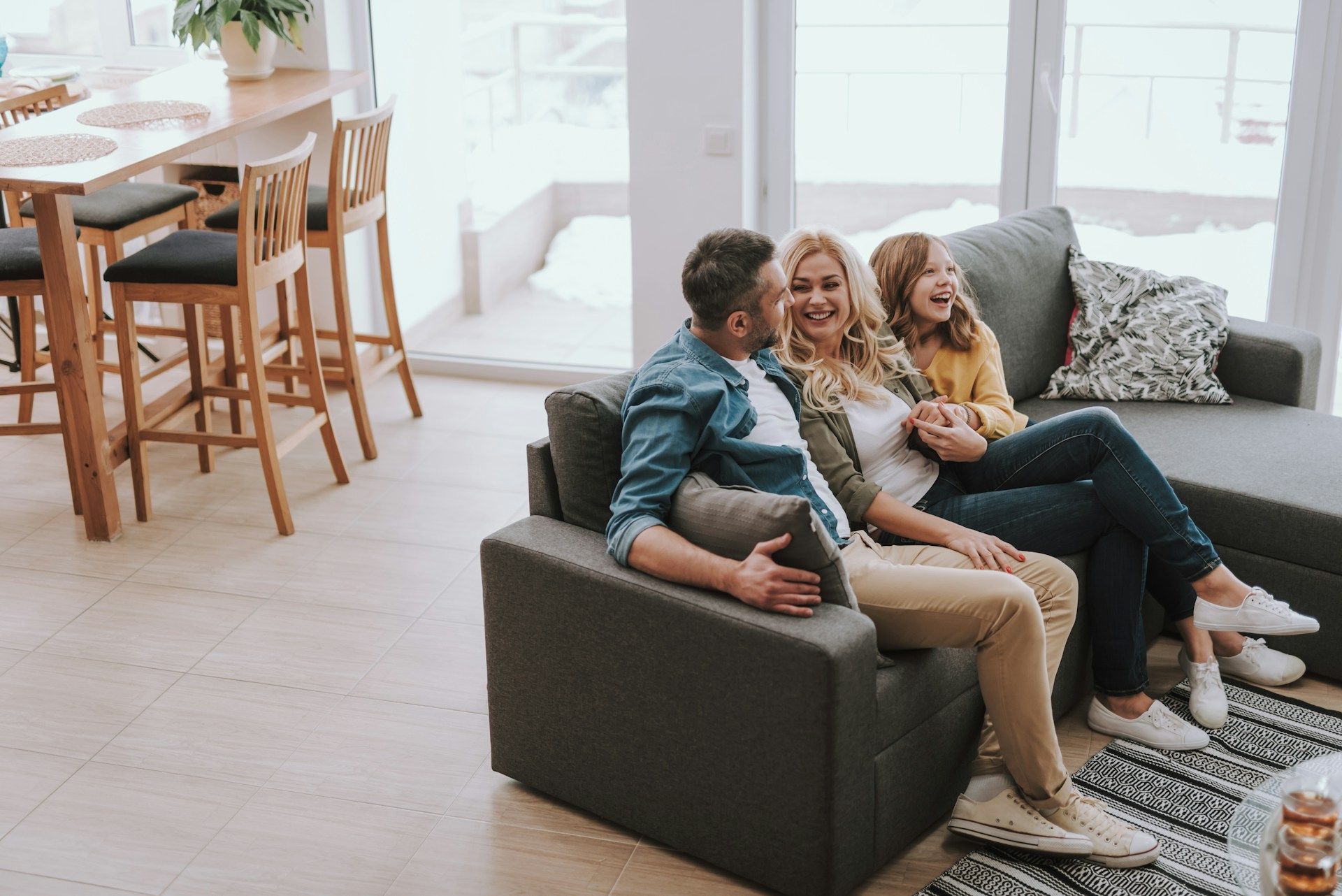 Family of three sitting on floor, interacting with a baby; near fireplace.