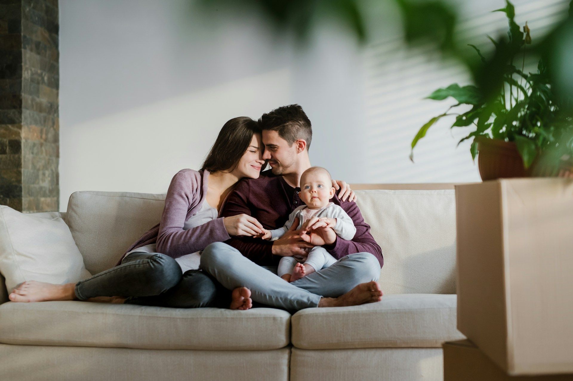 Family of three sitting on floor, interacting with a baby; near fireplace.