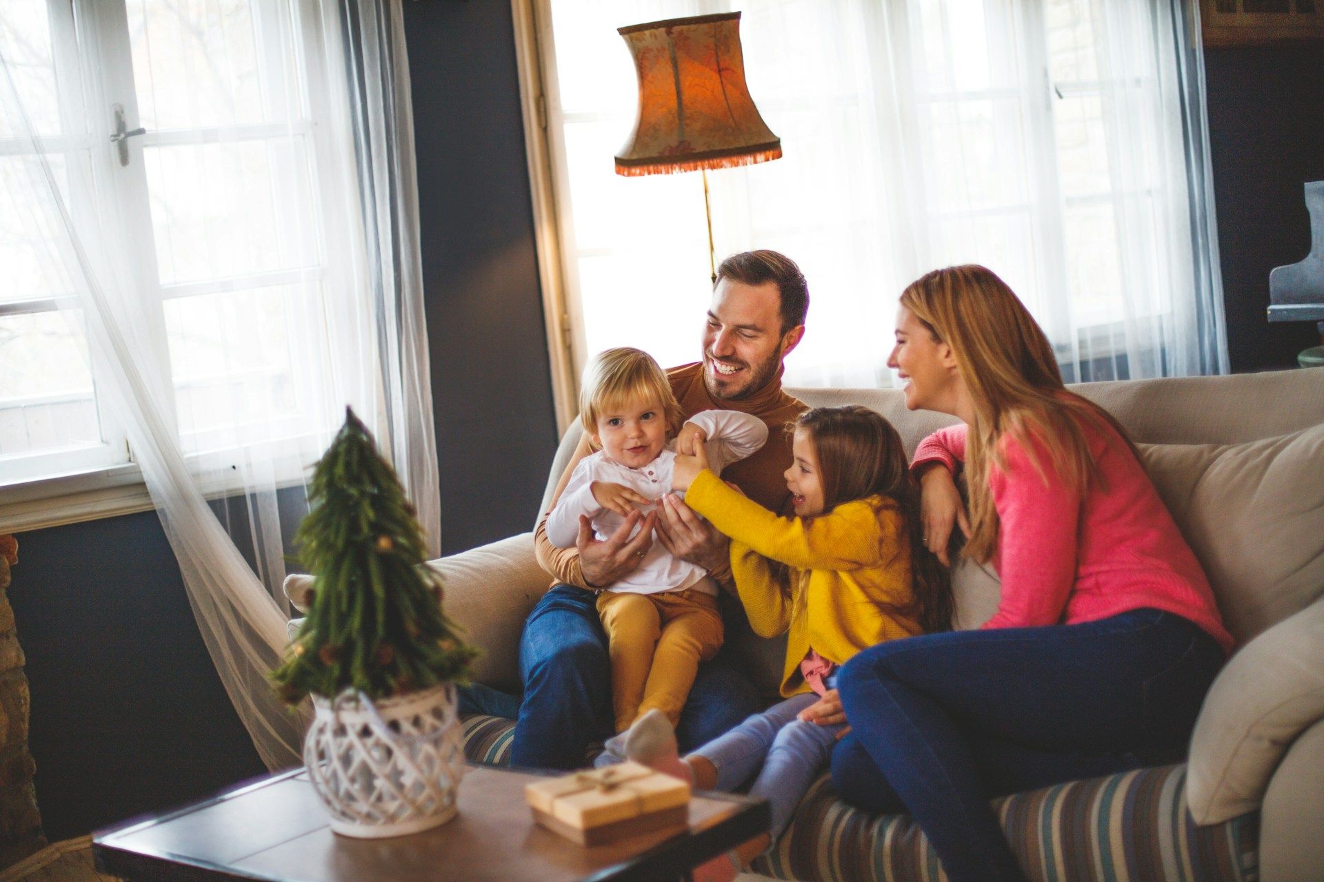 Family of three sitting on floor, interacting with a baby; near fireplace.