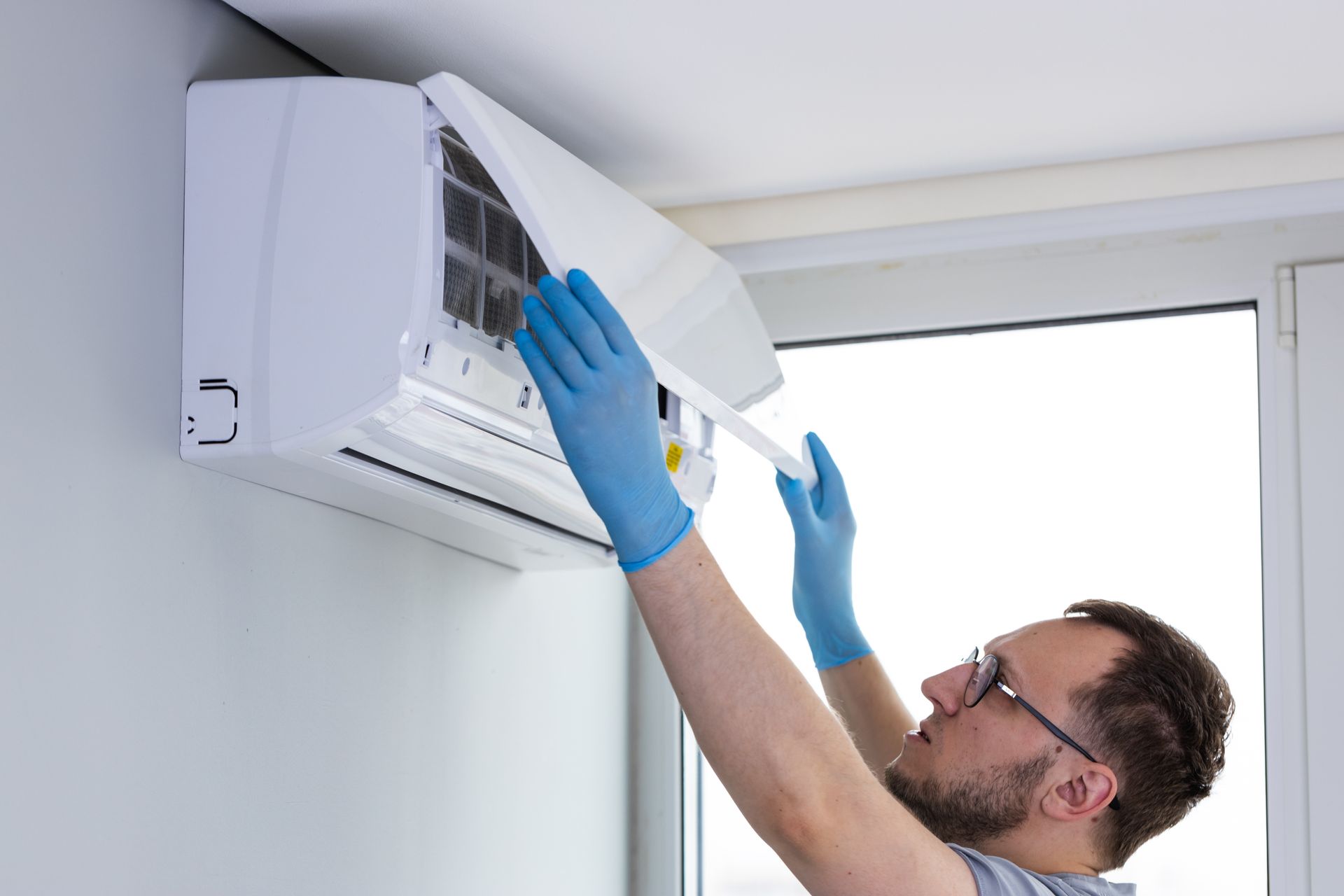 A technician opening an air conditioner unit to inspect and clean internal components. A technician opening an air conditioner unit to inspect and clean internal components.