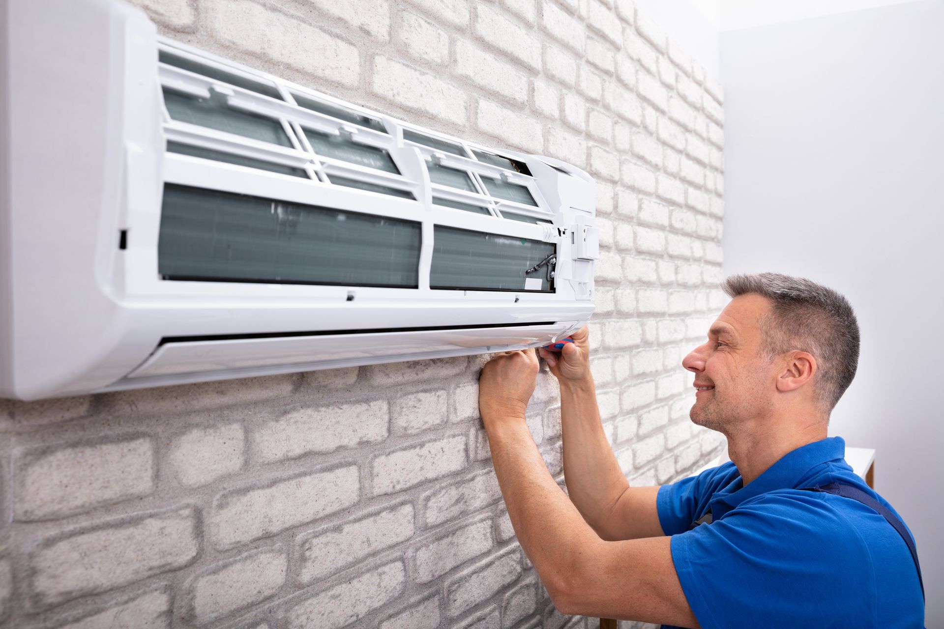 An air conditioning contractor fixing a unit, highlighting Sawyer Heating & Air Conditioning's servi
