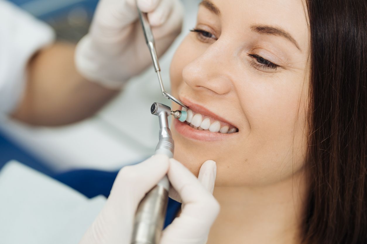 Dentist examining a patient’s teeth with dental tools, smiling in a clinic chair