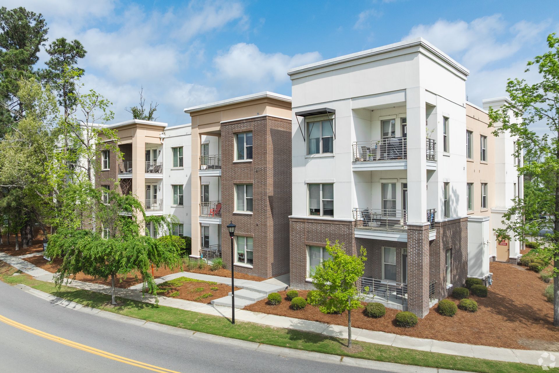 Modern apartment buildings with balconies and landscaping along a curved street