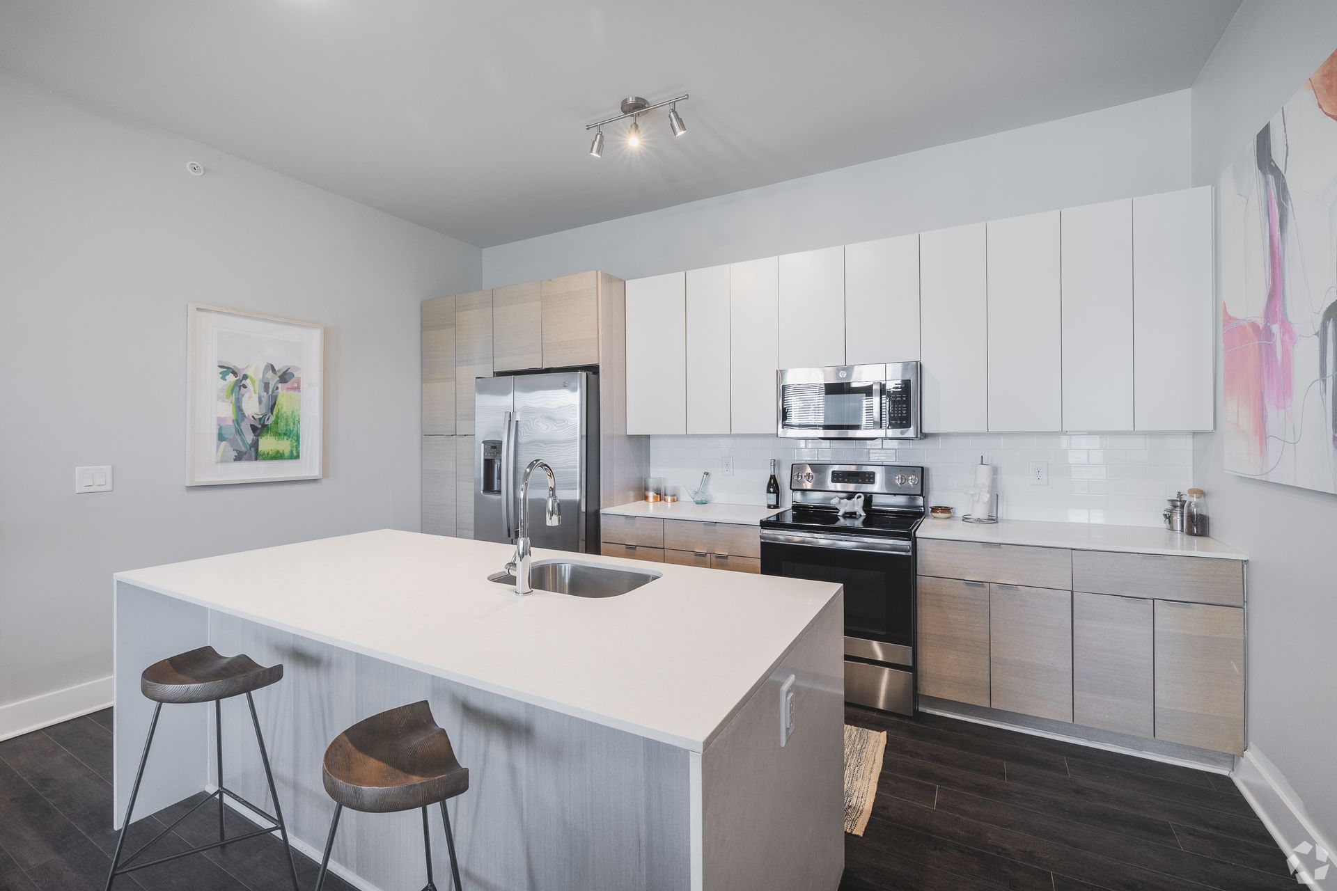 Modern kitchen with white cabinets, stainless appliances, and a large island with two stools