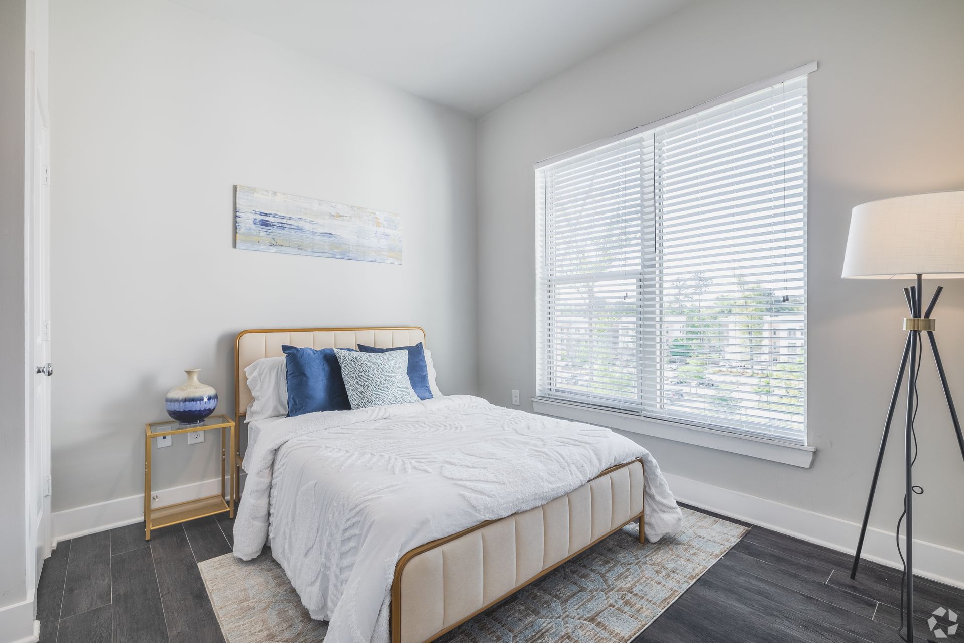 Bright minimalist bedroom with a bed, nightstand, window blinds, and a floor lamp