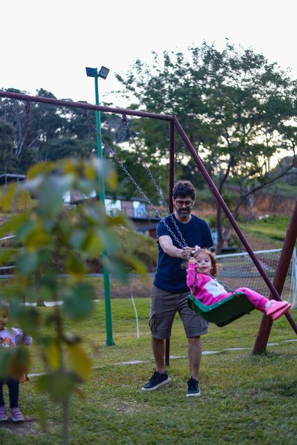 Casal sentado em um banco compartilhando bebidas sob luzes de corda aconchegantes à noite.