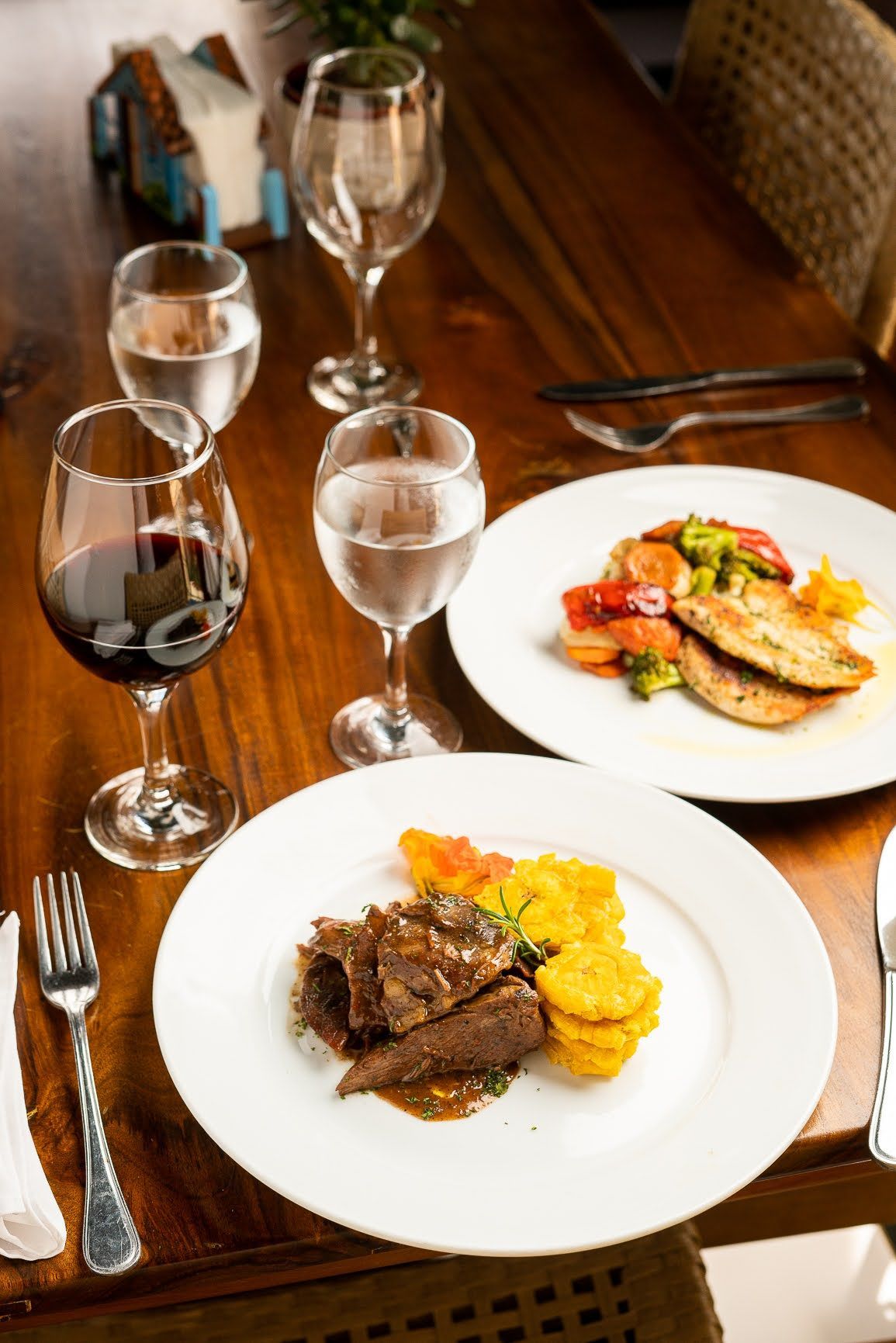 Una mesa de madera cubierta con platos de comida y copas de vino.