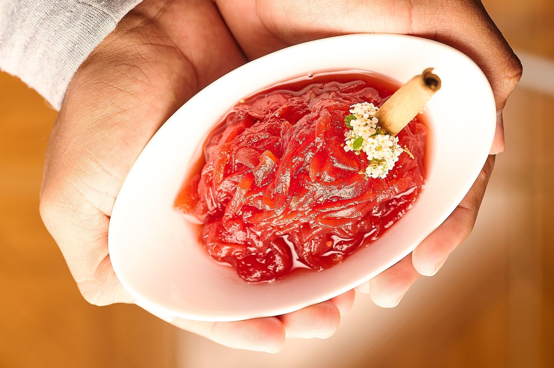 Una persona sostiene un plato de salsa de arándanos con una ramita de canela