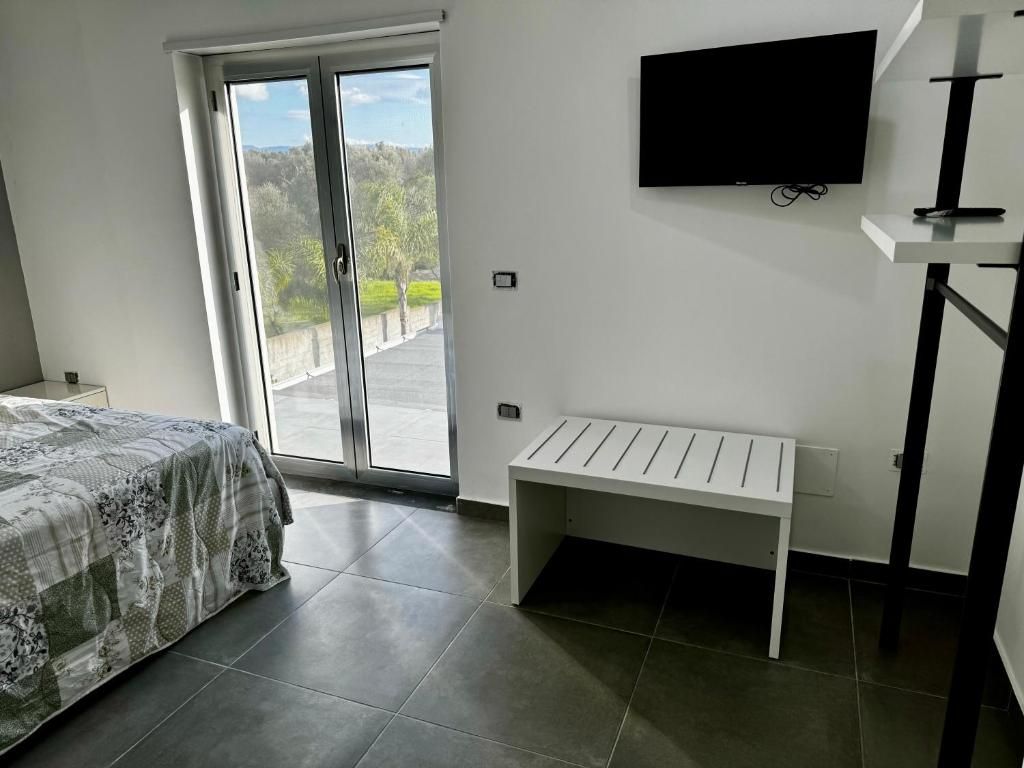 Una camera con un letto, televisione e porte scorrevoli in vetro.
