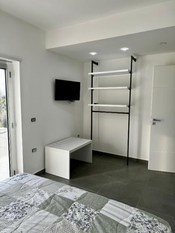 Una camera da letto con letto, televisione, scaffali e porta scorrevole in vetro.