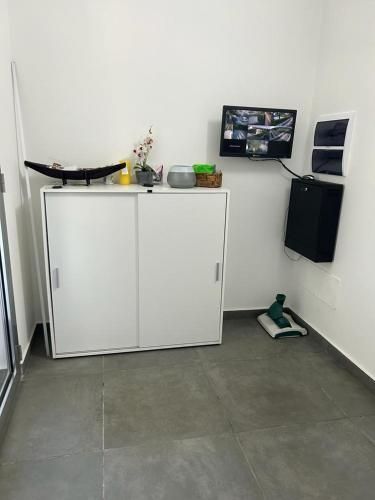 Una stanza con un mobiletto bianco e un televisore alla parete.