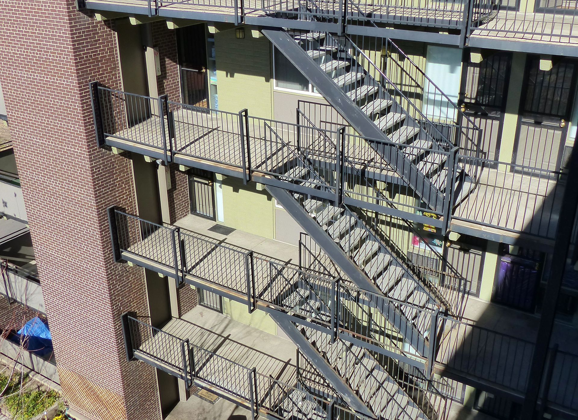 Outdoor apartment building with metal fire escapes and brick walls in bright sunlight