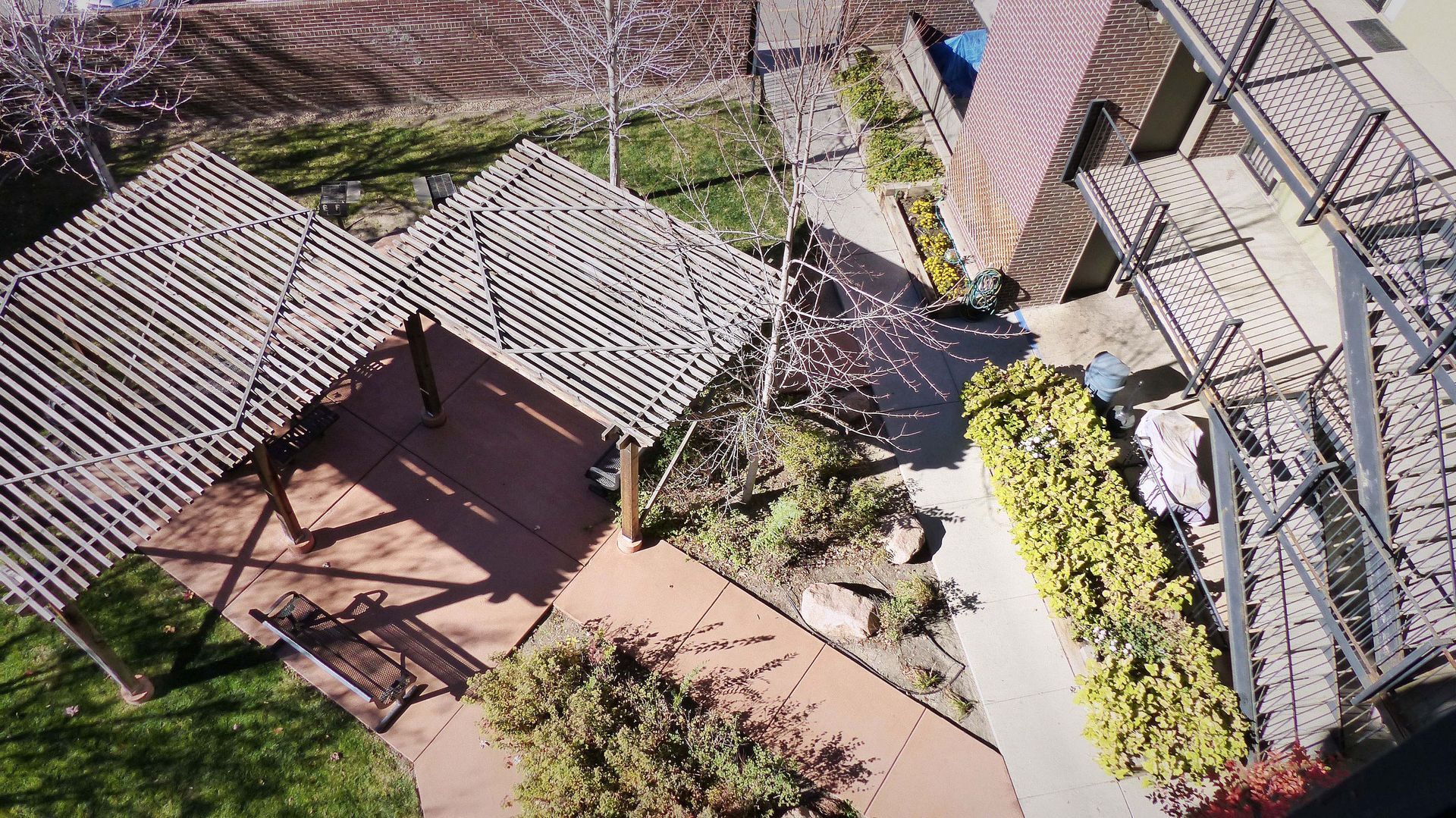 Aerial view of a courtyard with tiled-roof pergolas, brick paths, and landscaped greenery.