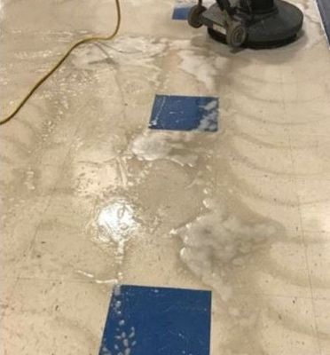 A person is cleaning a tile floor with a machine.