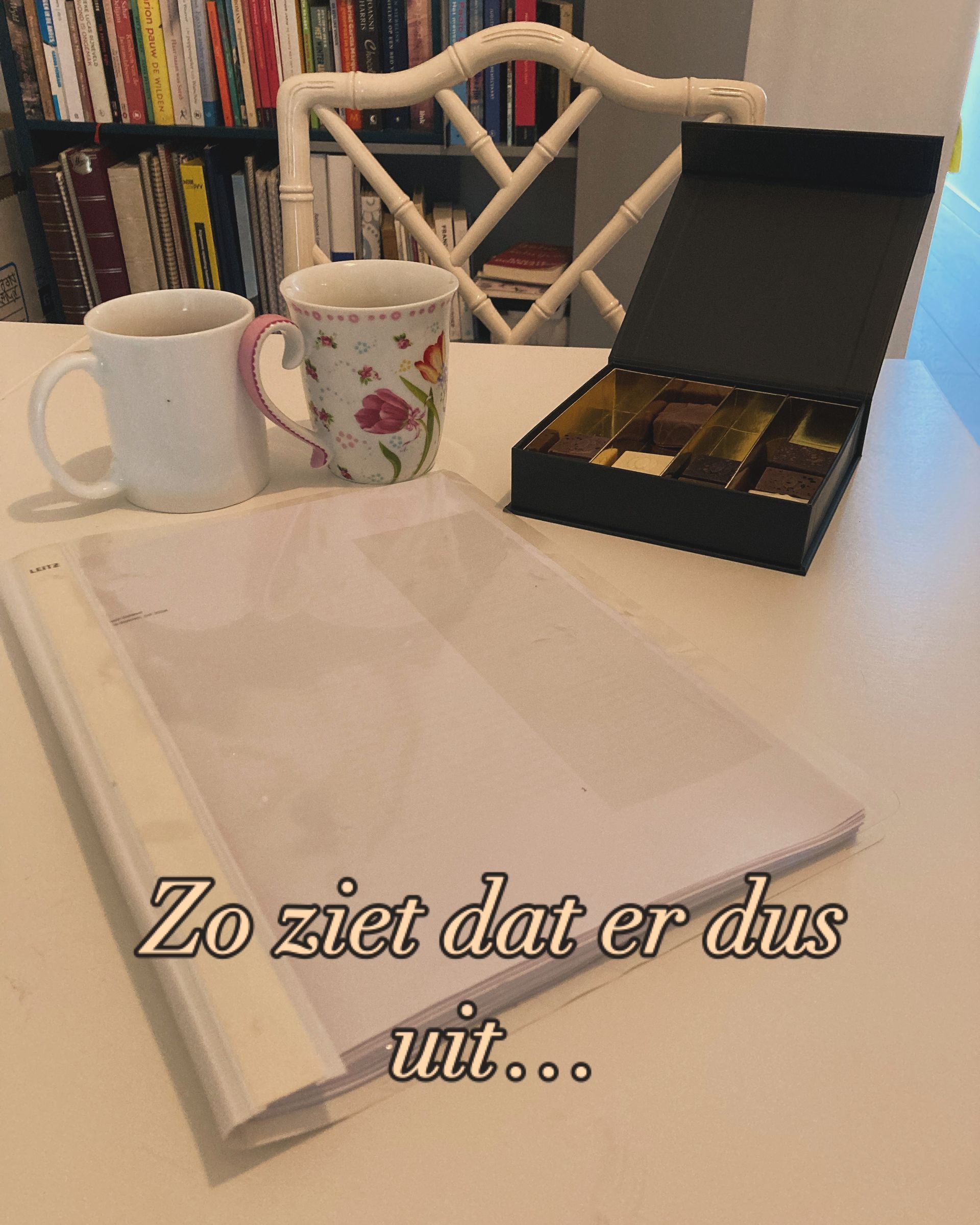 Two mugs, box of chocolates, and paper on a table, with text: 