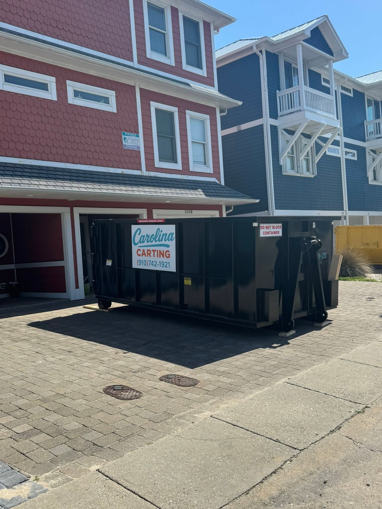 Apartment building with a large black dumpster parked in front of red and blue beach-style condos