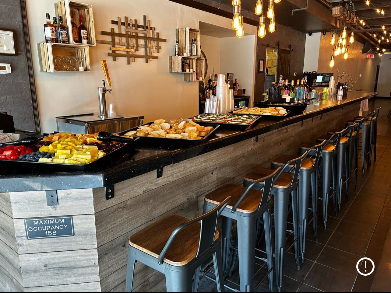 Bar counter with food displays and stools, lit by overhead lights.
