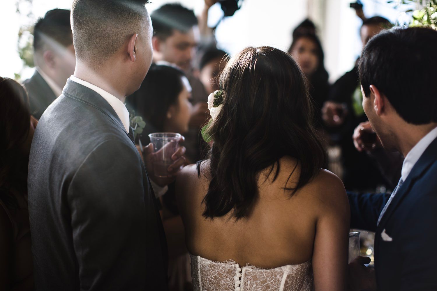 Bride in wedding dress, surrounded by guests, drinks, and laughter.