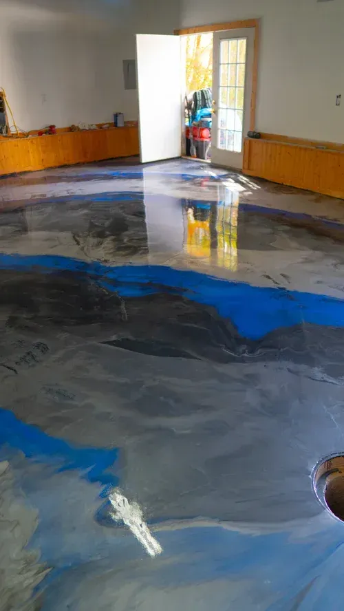 A room with a polished, marbled-effect resin floor in shades of gray, black, and bright blue, leading to an open doorway.