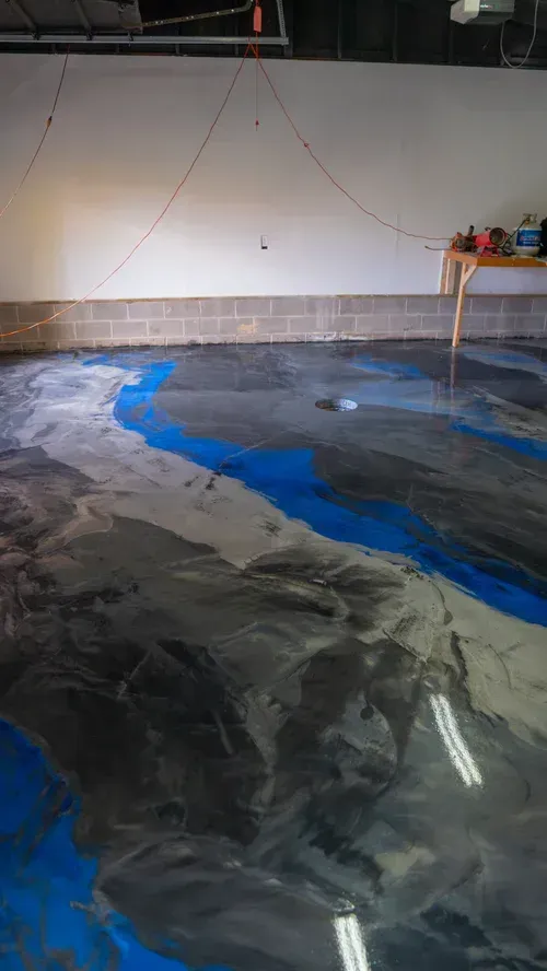 A garage floor with a glossy, marbled epoxy finish featuring swirling patterns of deep blue, grey, and white.