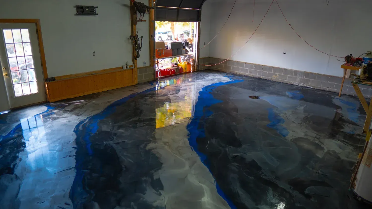 A workshop with a glossy epoxy floor featuring a swirling, marbled pattern of deep blue, grey, and white colors.