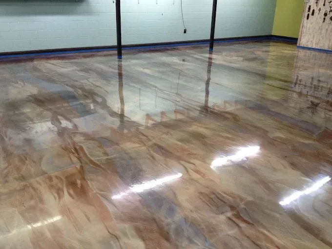 A polished concrete floor with a glossy, marbled epoxy finish in swirling shades of beige, brown, and metallic gray.