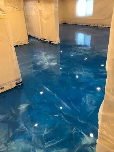 A room with a polished, glossy blue metallic epoxy floor featuring swirling white marble-like patterns.