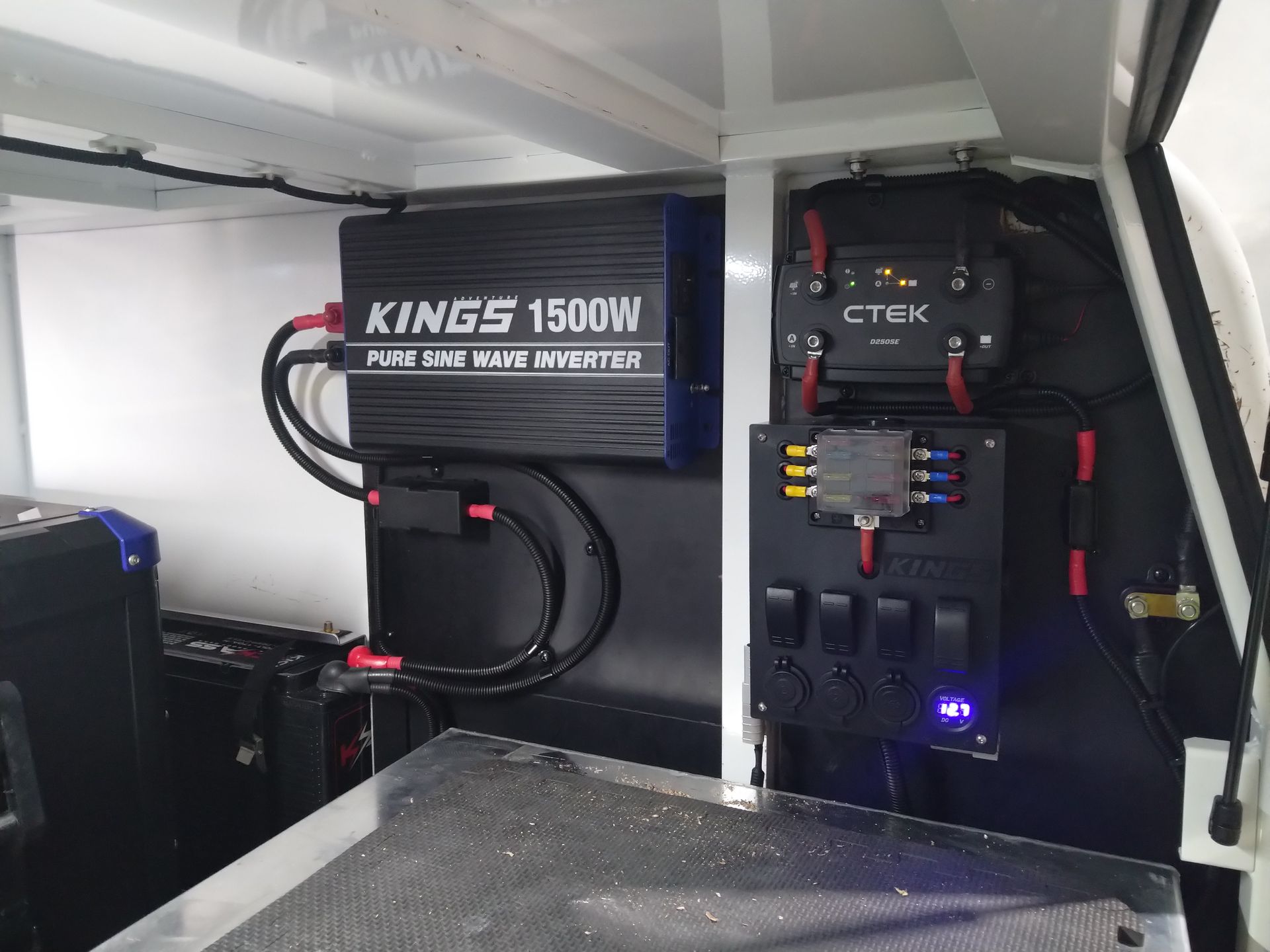 Black 1500W inverter and electrical panel with switches and outlets installed inside a vehicle.