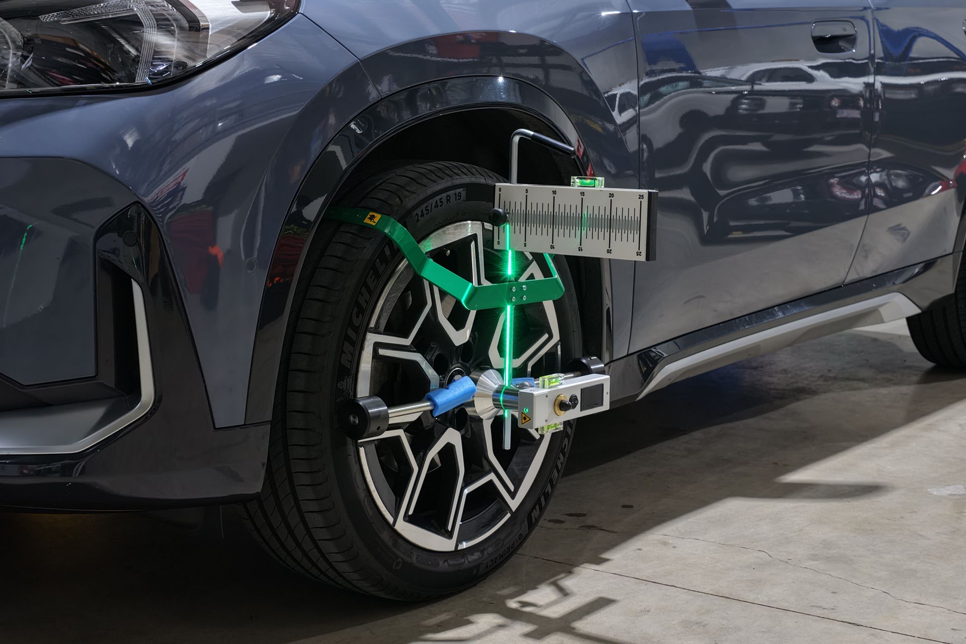 Car wheel aligned with green laser guides in a garage.