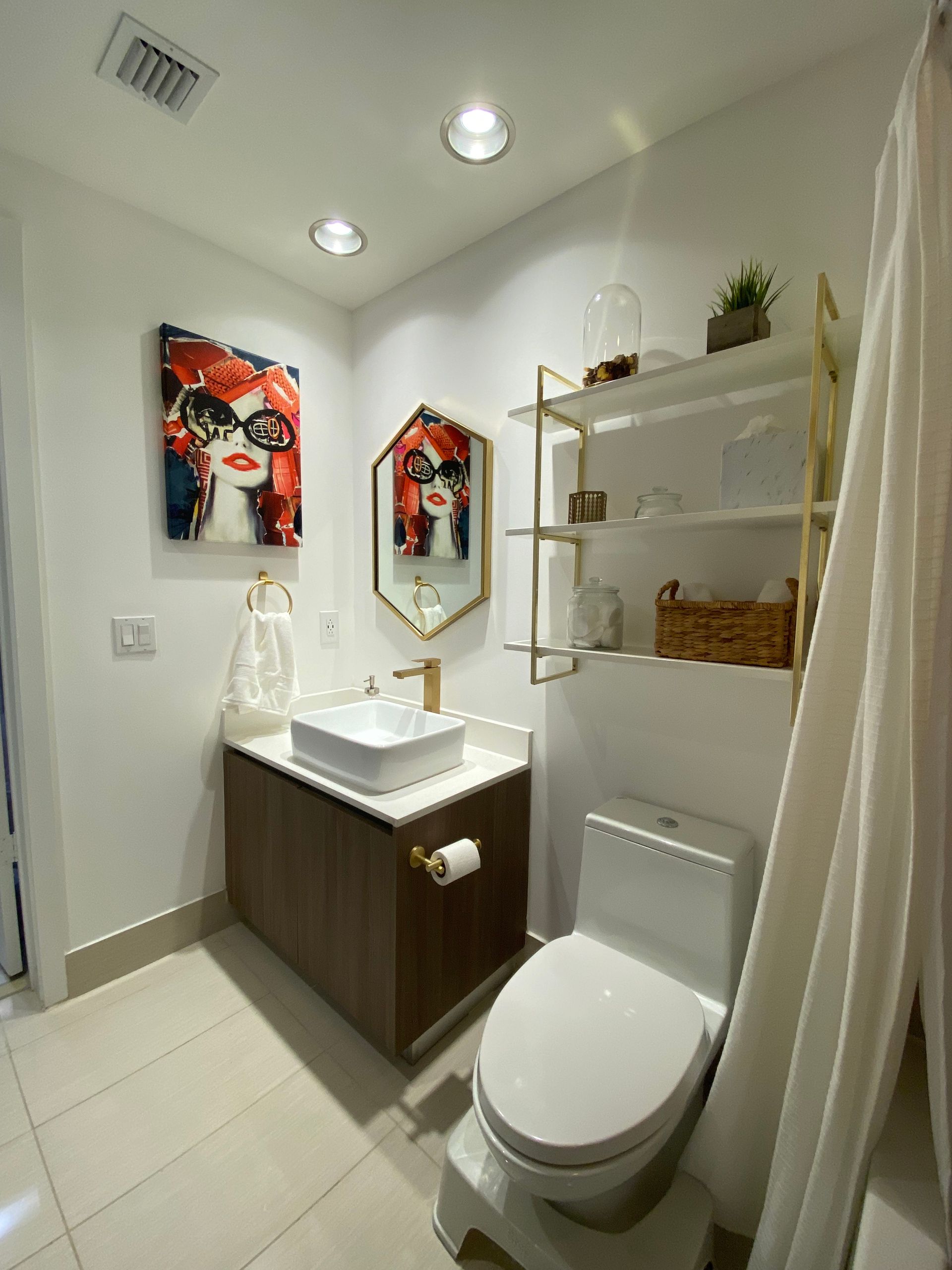 Modern white bathroom with wood vanity, toilet, mirror, open shelves, and shower curtain
