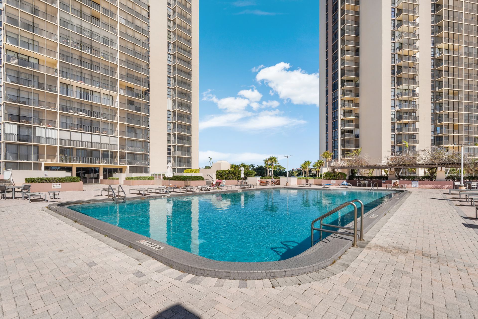 High-rise apartment courtyard with a large turquoise swimming pool and sun loungers