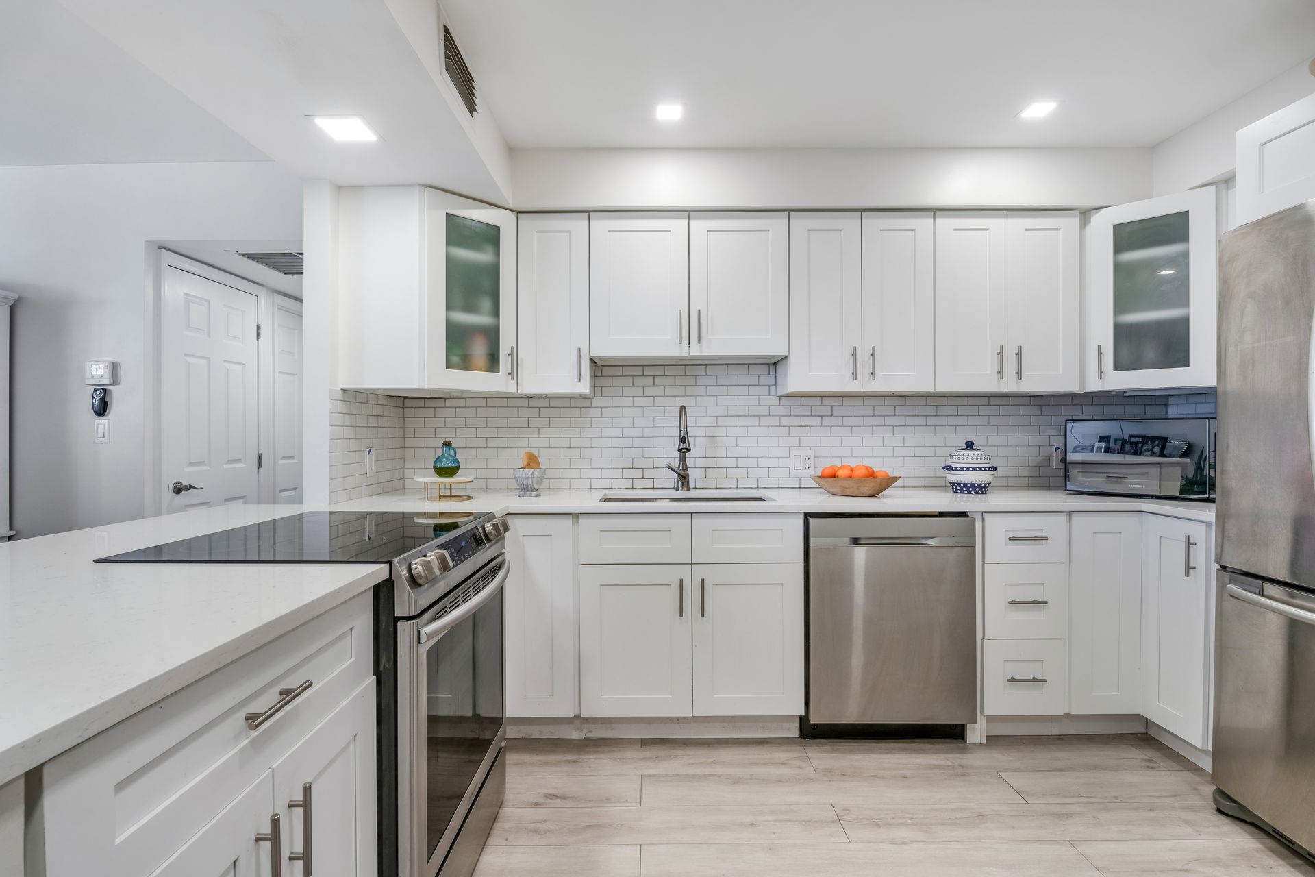 Bright modern white kitchen with stainless steel appliances, island, and tiled backsplash