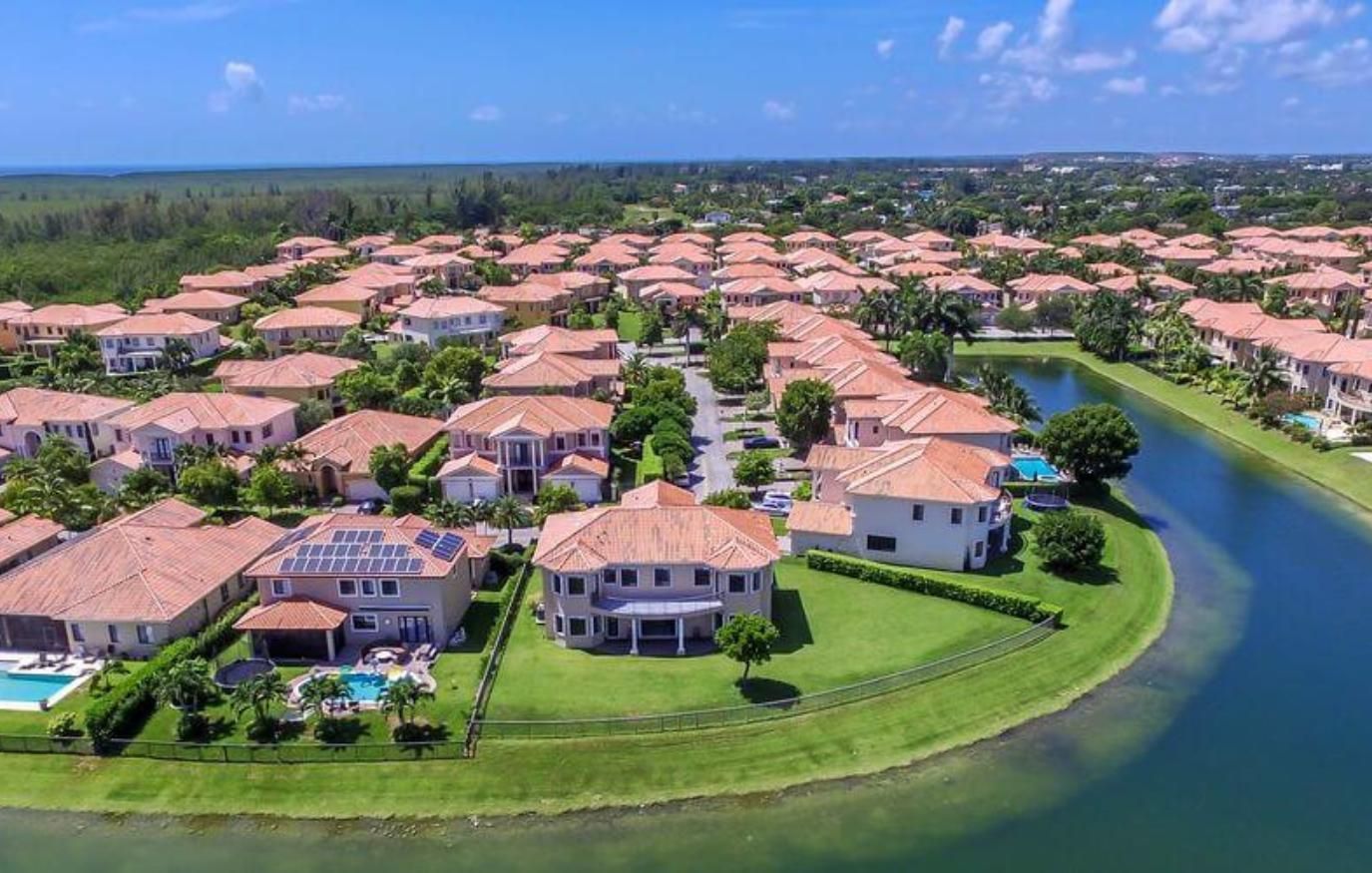 Aerial view of a waterfront suburban neighborhood with tan-roofed homes and winding canals.
