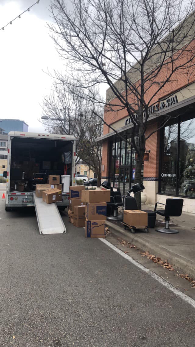 A moving truck filled with boxes is parked in front of a building.