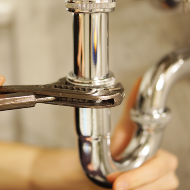 A person is fixing a pipe with a wrench.