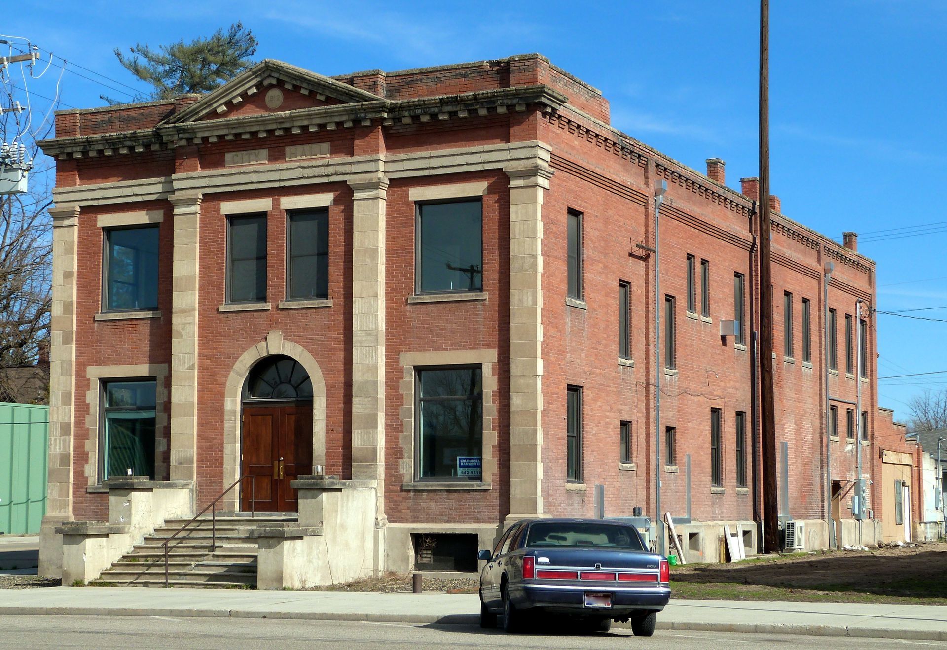 Red brick building with stone accents, car parked out front.