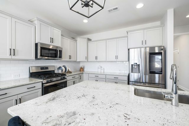 White kitchen with granite countertops, stainless steel appliances, and island.