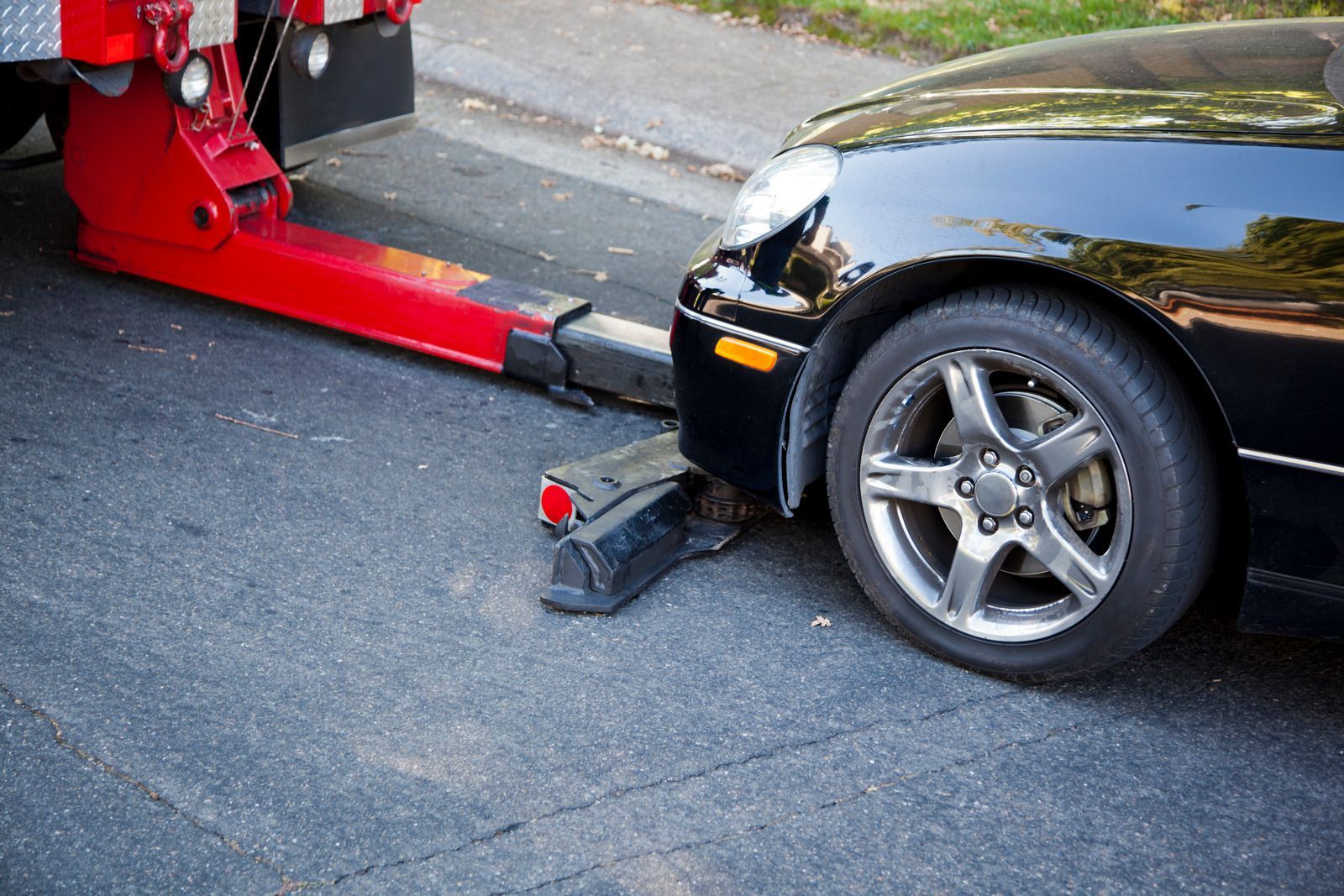 A black car is being towed by a tow truck.