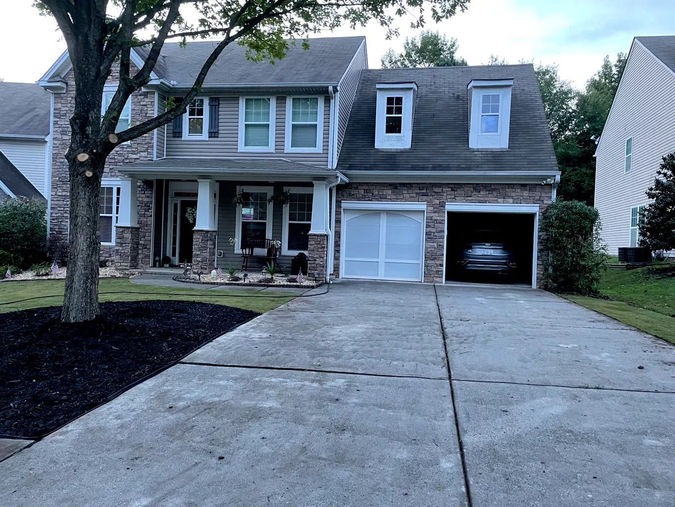 Suburban two-story house with driveway, garage, and front porch in a residential neighborhood