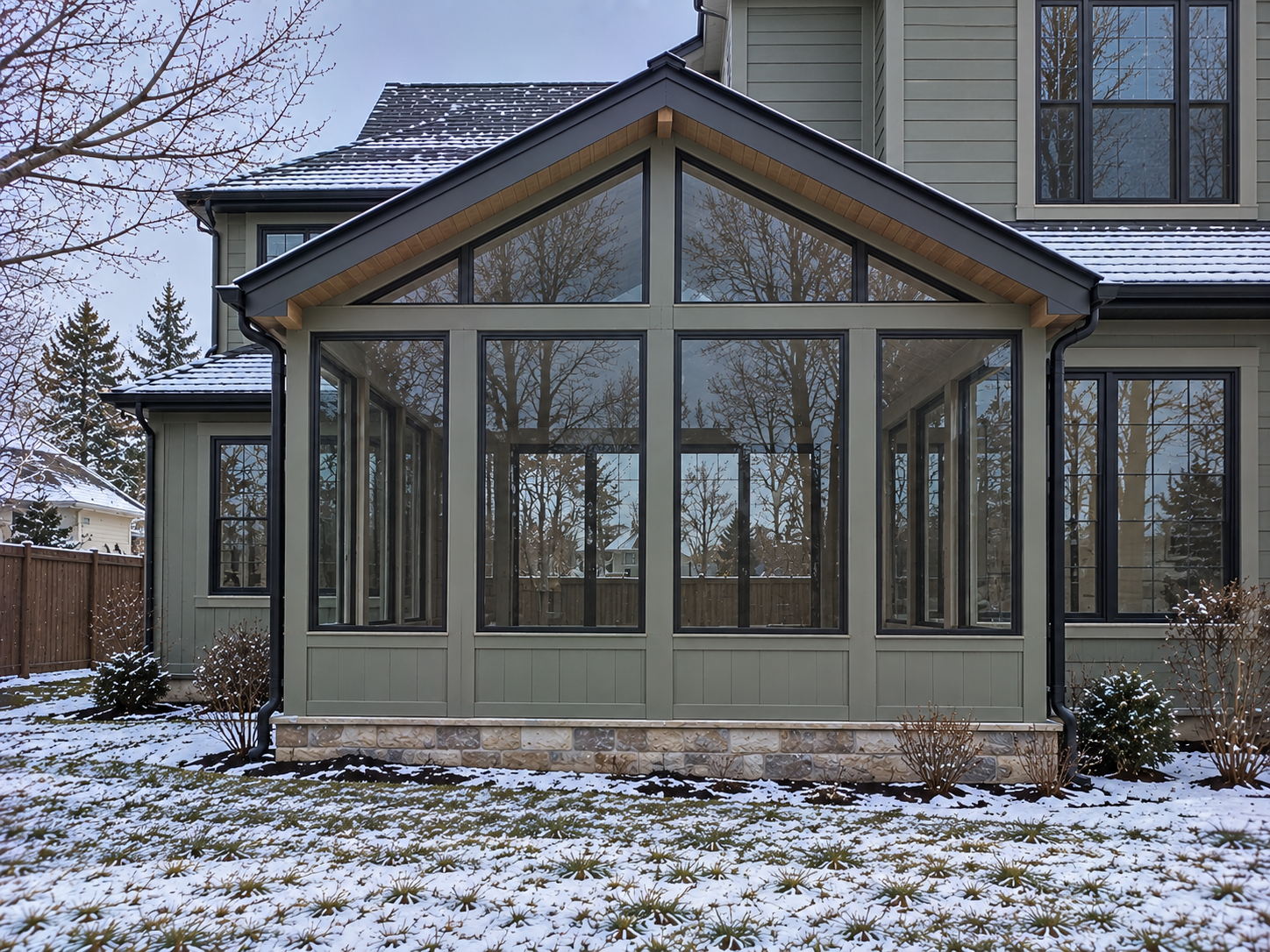 Green sunroom with a gable glass front and stone base built by Colorado Outdoor Builders in Aurora, Colorado