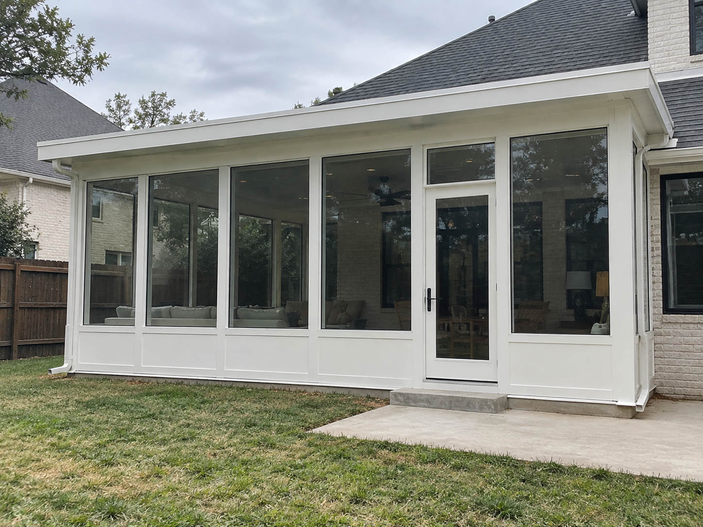 White sunroom with floor-to-ceiling glass and a glass entry door built by Colorado Outdoor Builders in Englewood, Colorado