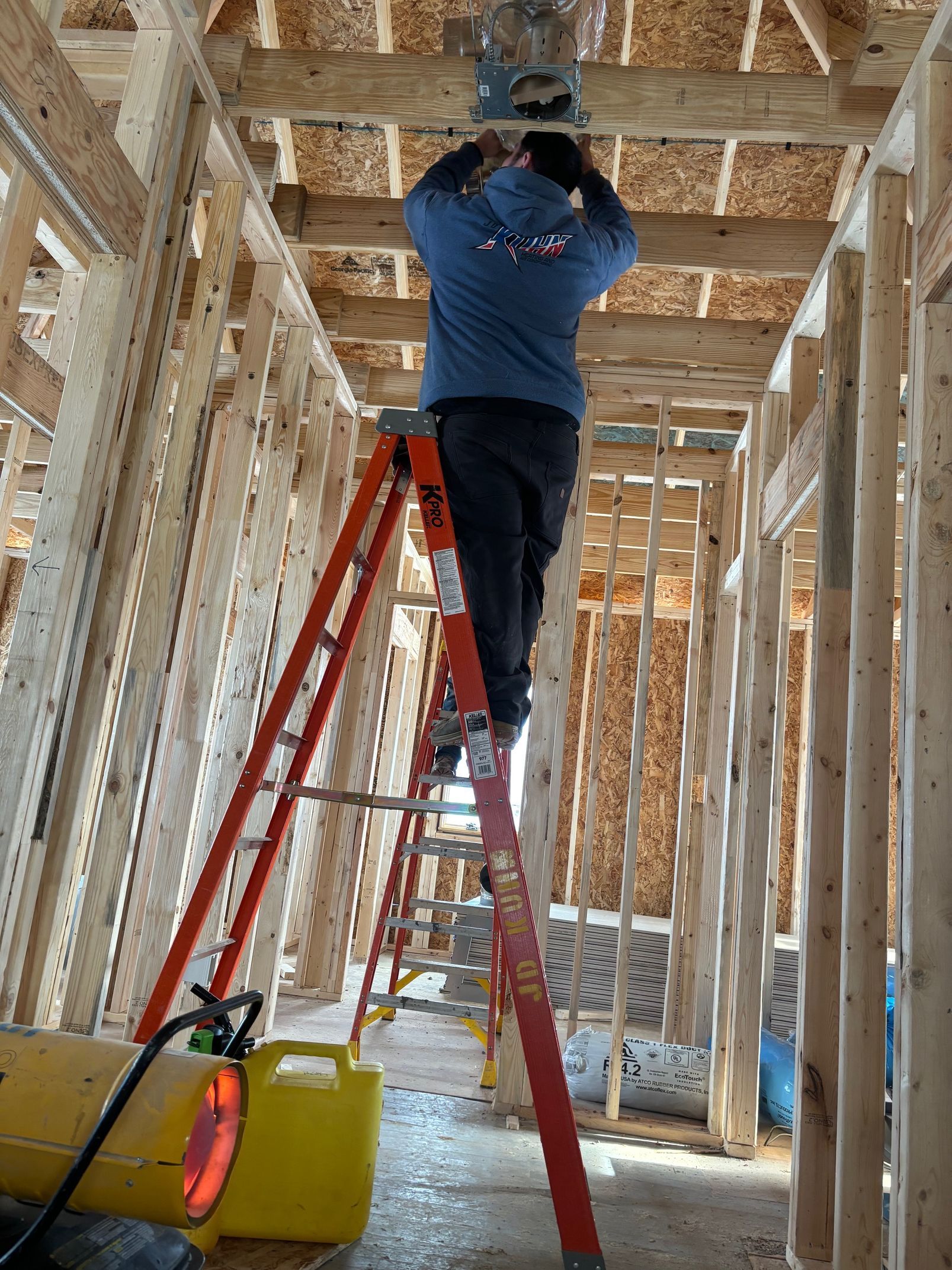 A man is standing on a ladder in a building under construction.